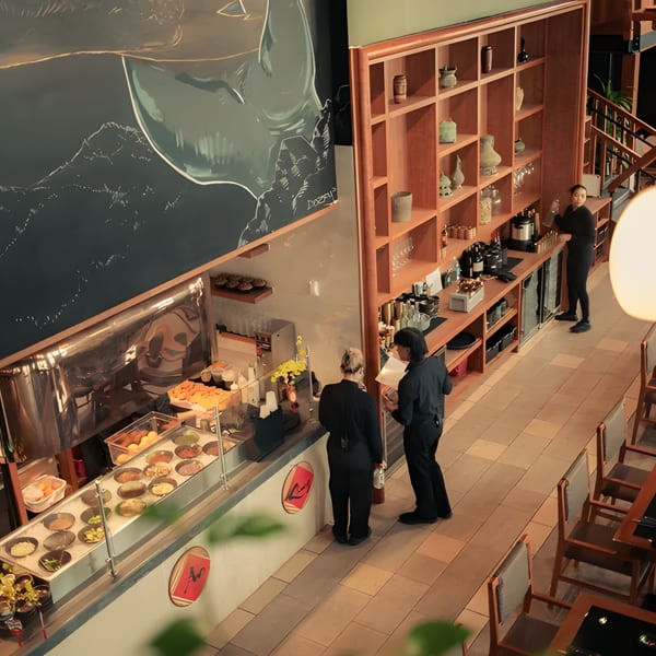 Overhead view of a modern restaurant interior with a food counter, dining tables, and staff.