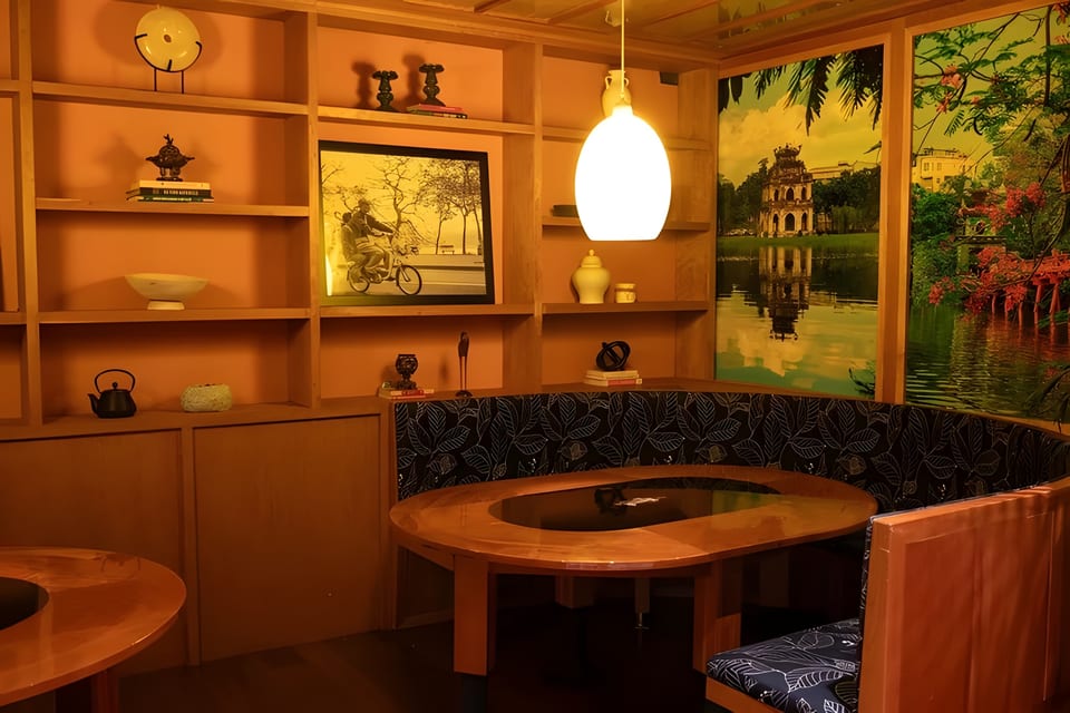 A cozy restaurant booth with a wooden table, shelves, and large scenic wall art.